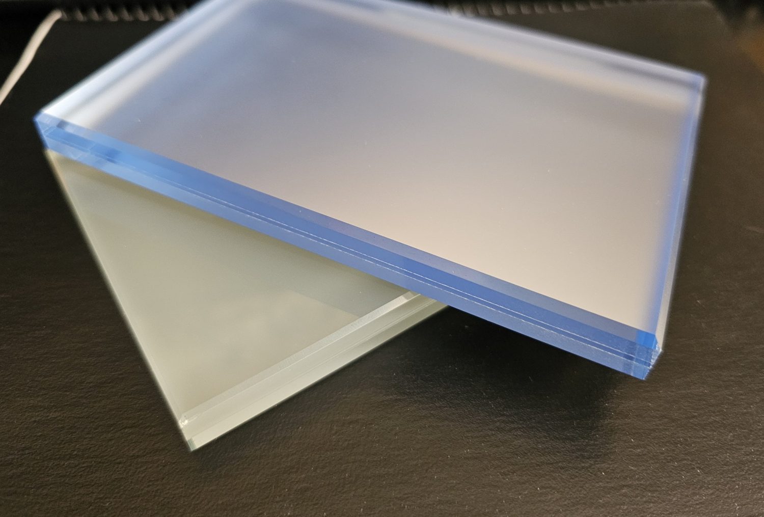 Blue glass sample with a velour surface and a mirror bonded behind it, resting on a clear frosted glass sample