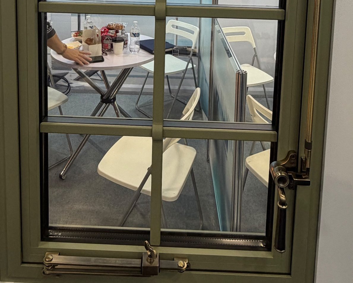 Lower half of the aluminium casement sample: horizontal divided-lite muntins, a brass casement stay bar across the sill and a brass lever handle