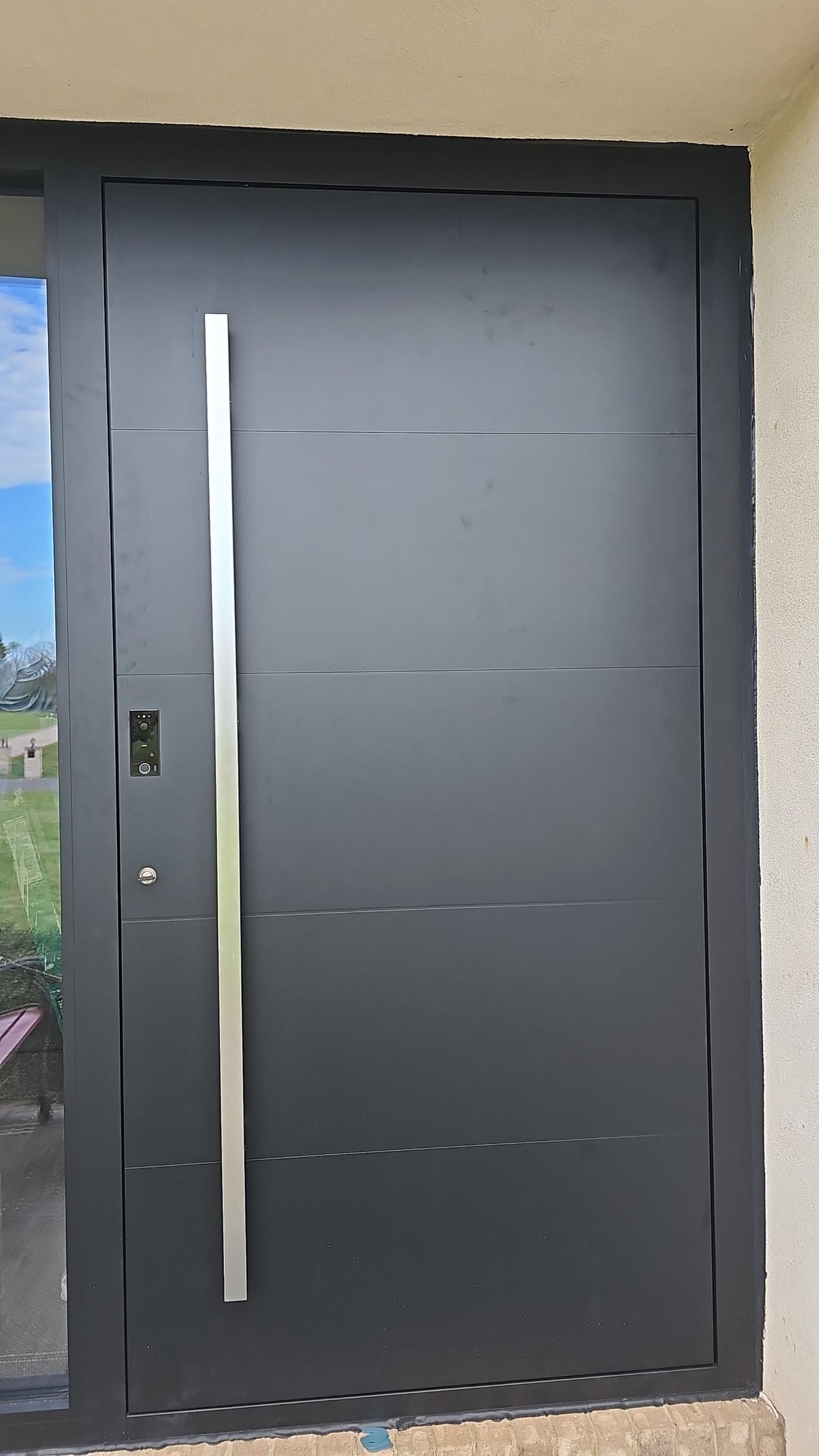 The entrance door: flush black aluminum leaf, full-height pull, fingerprint reader