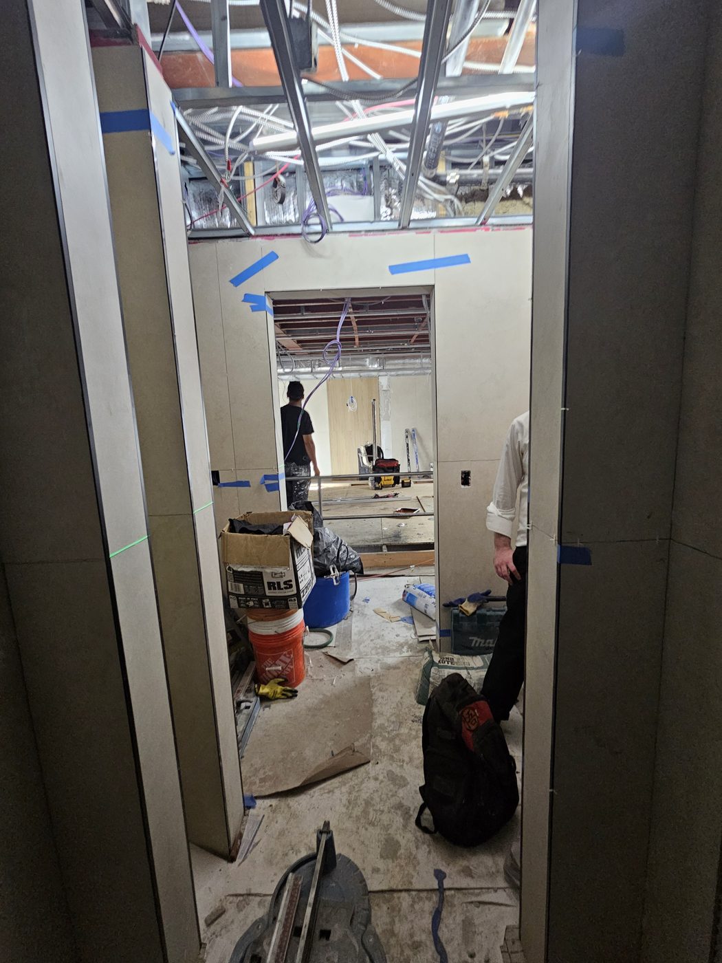 Bathroom corridor at 2555 Nostrand Avenue, Midwood, with porcelain wall panels set and the door opening being surveyed