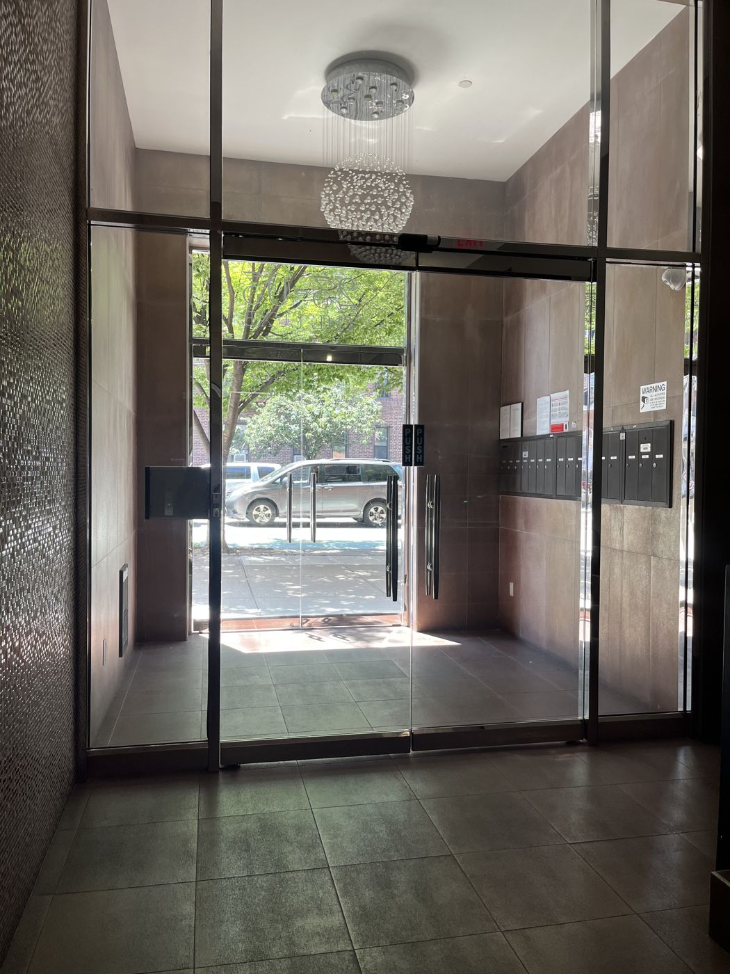 Frameless glass vestibule doors with full-height pulls in the lobby of an apartment building in Astoria, Queens