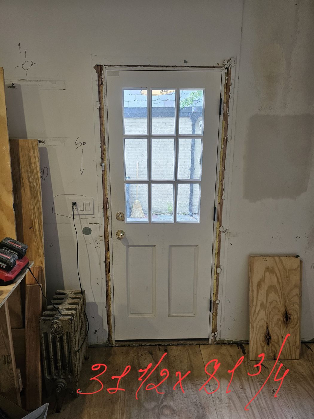 Existing nine-lite door seen from inside with the trim removed, marked 31 and a half by 81 and three quarter inches