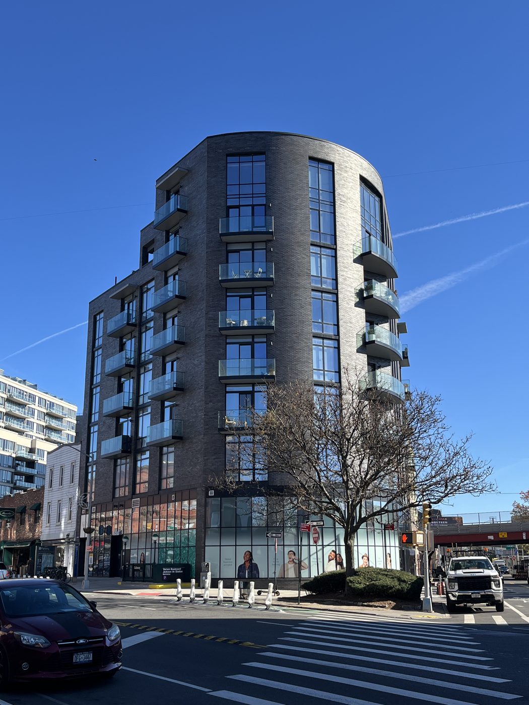 The Anable at 10-64 Jackson Avenue, Long Island City: curved brick corner with columns of Cortizo curtain wall, stacked curved glass balconies and a curved storefront at grade