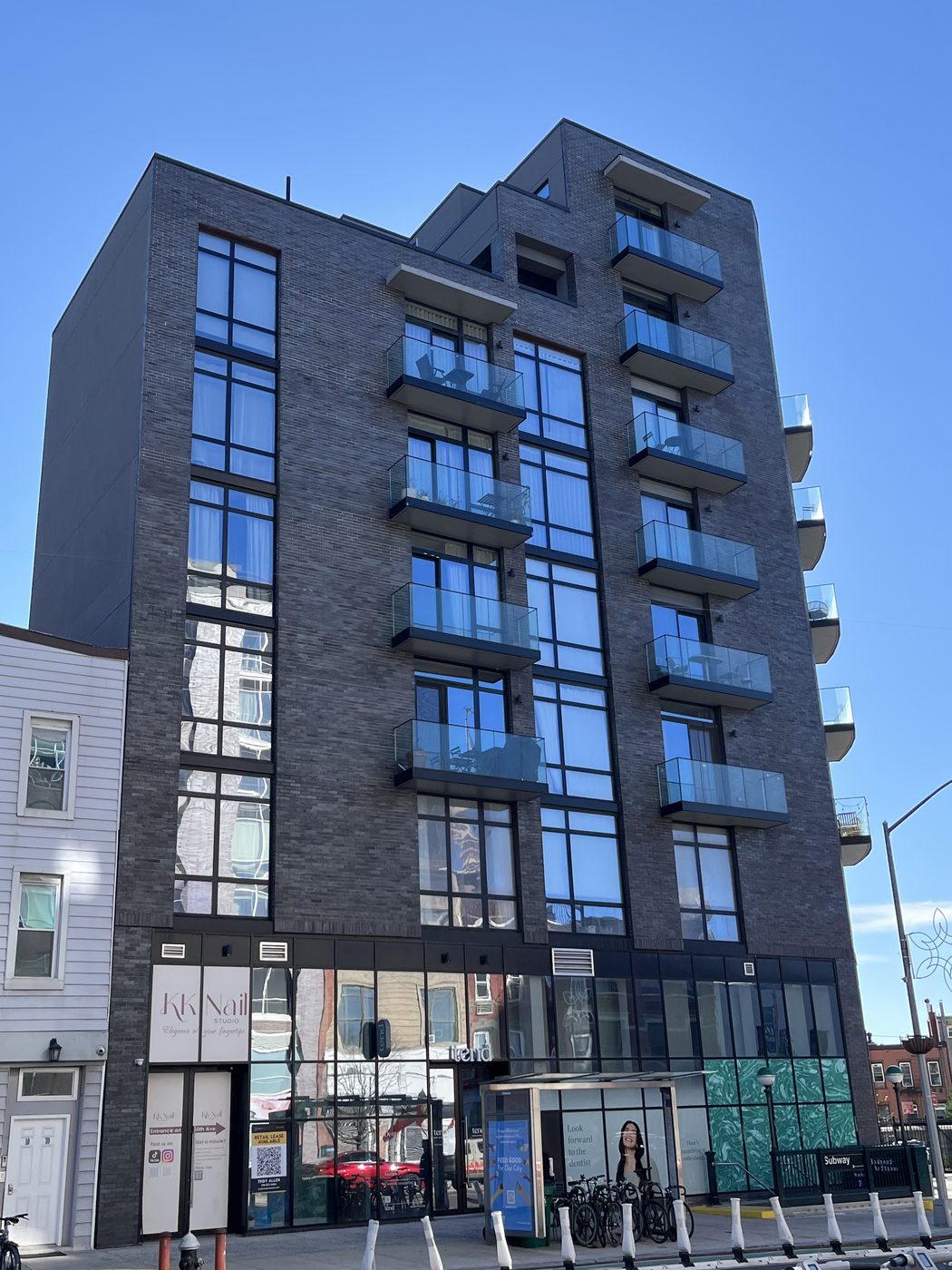 50th Avenue elevation of The Anable with sliding balcony doors in the curtain wall and retail storefront below