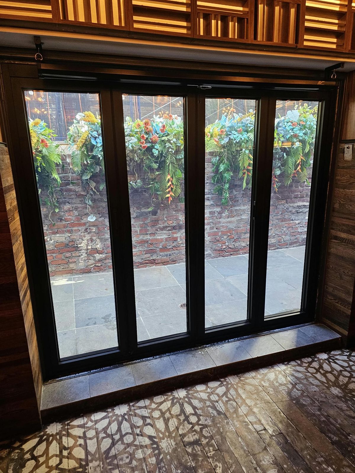 Four-panel black thermally broken aluminum bifold door between a restaurant dining room and its patio, East Village, Manhattan