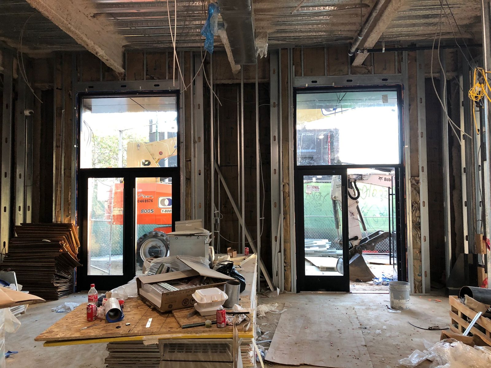Interior view during construction of two storefront openings at 1209 Vine Street, Philadelphia: a pair of black aluminium doors with a transom on the left and a single door with a transom on the right