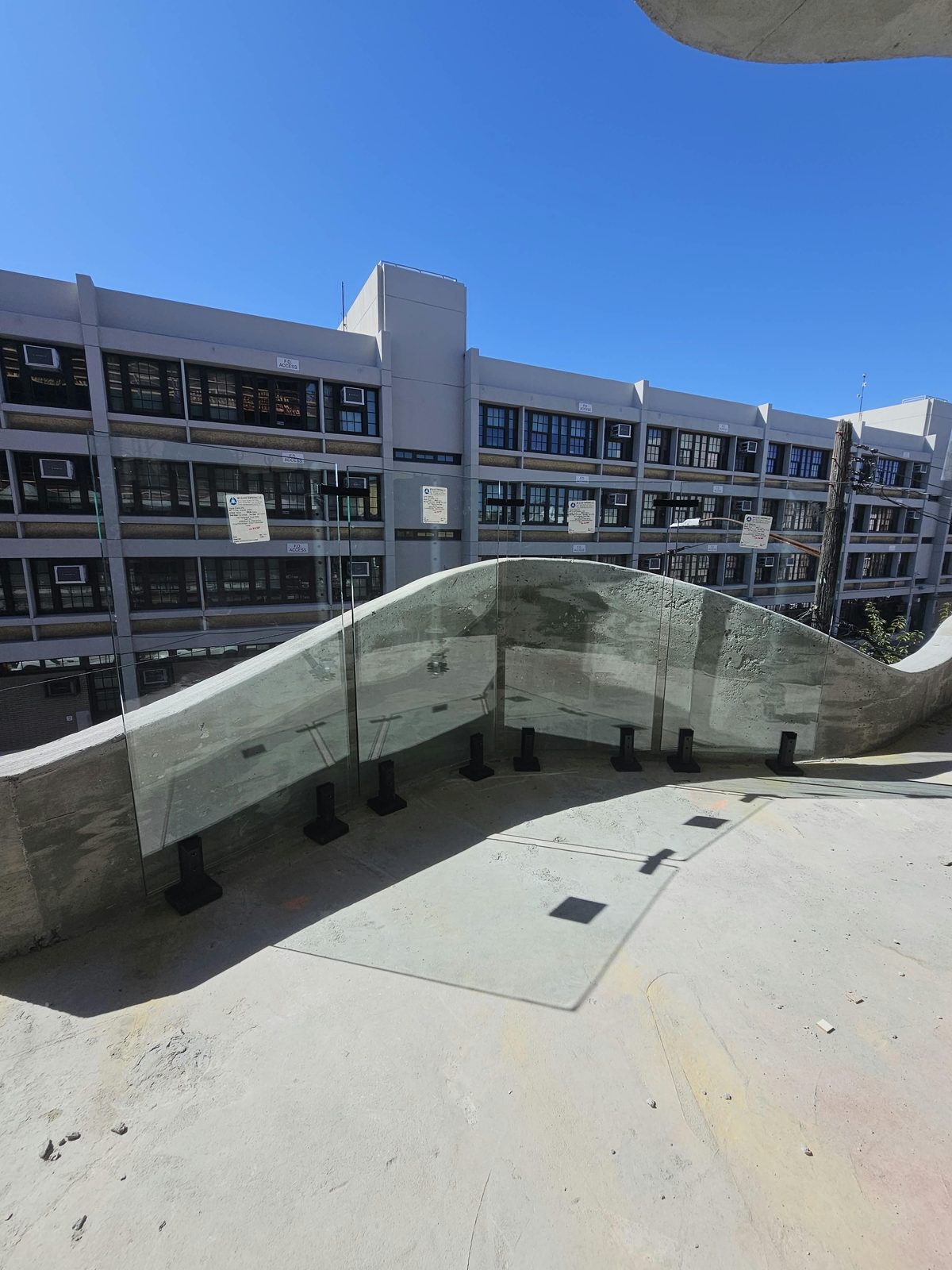 Faceted glass guard mock-up on spigot clamps at the crest of the wave parapet at 1505 Emmons Avenue, glass labels still on