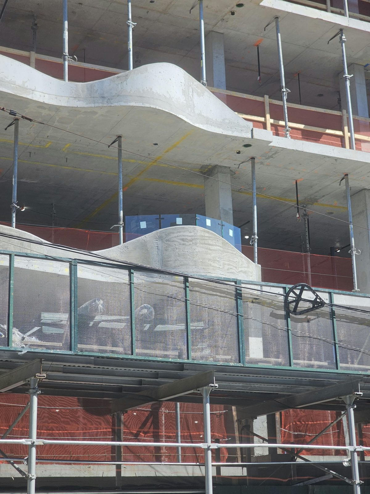Wave-form balcony slabs at 1505 Emmons Avenue with the glass railing mock-up visible on the lower balcony