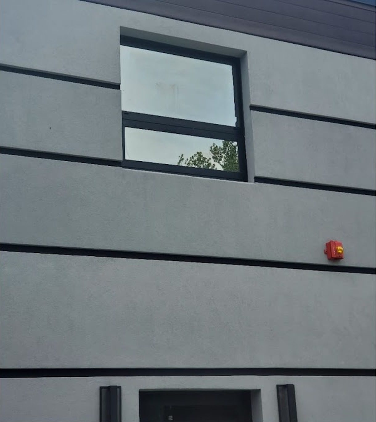 Gray stucco facade with a dark-framed window at the office building at 1545 Route 202, Pomona, NY