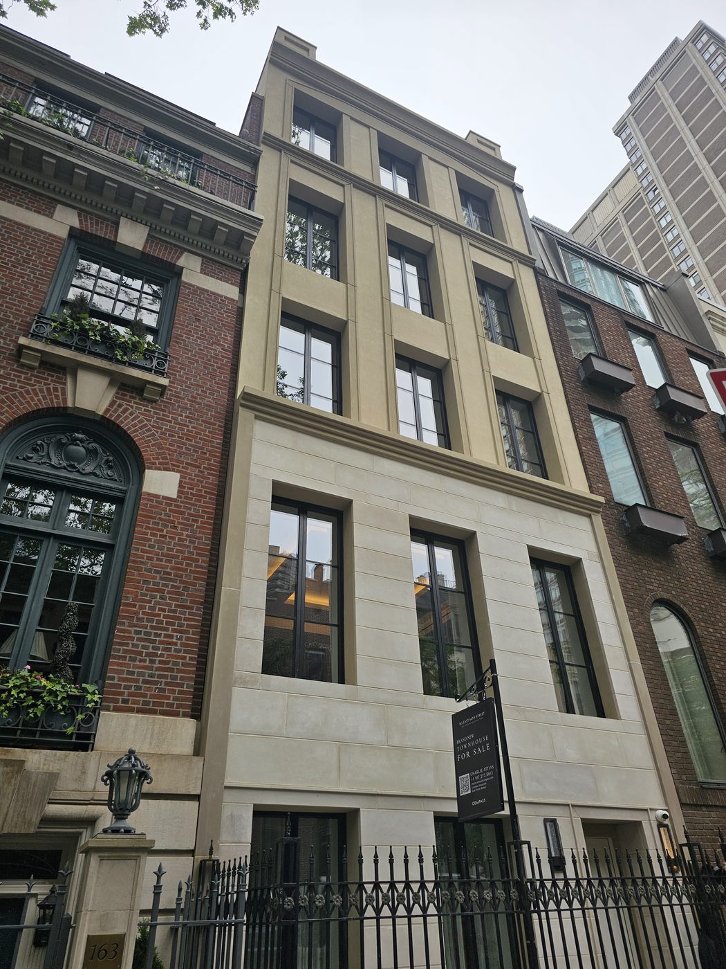 Limestone street facade of 165 East 64th Street townhouse, Upper East Side, with dark Cortizo aluminum tilt-and-turn windows