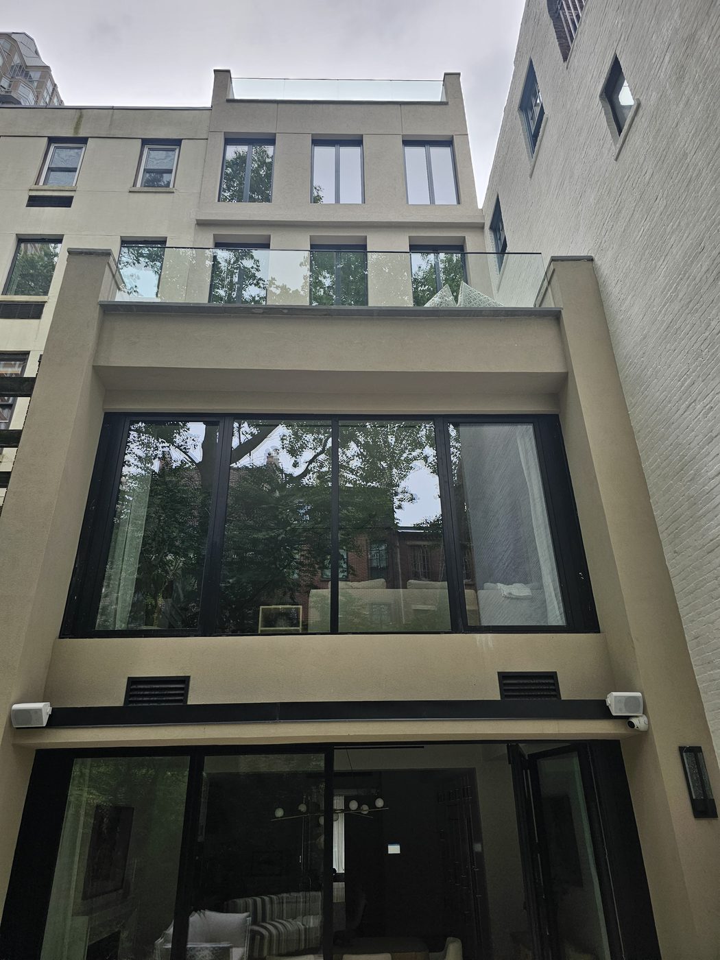 Rear elevation of 165 East 64th Street with floor-to-ceiling Cortizo glazing, garden bifold doors and frameless glass terrace railing