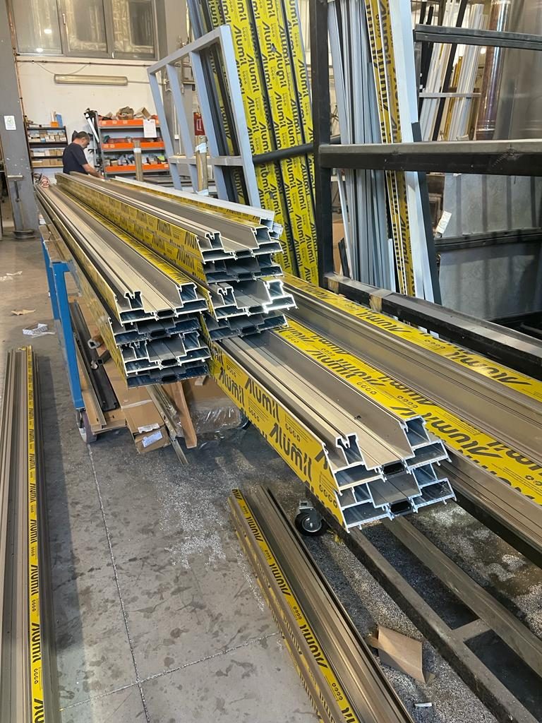 Cut Alumil aluminum profiles with polyamide thermal breaks stacked on a trolley in the fabrication shop for 201 Park Avenue, Monmouth Beach
