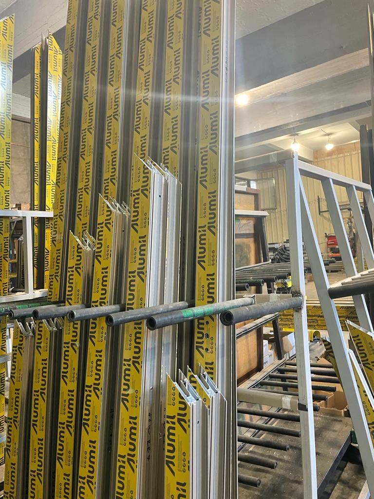Full-length Alumil aluminum profiles in protective tape standing in a vertical rack