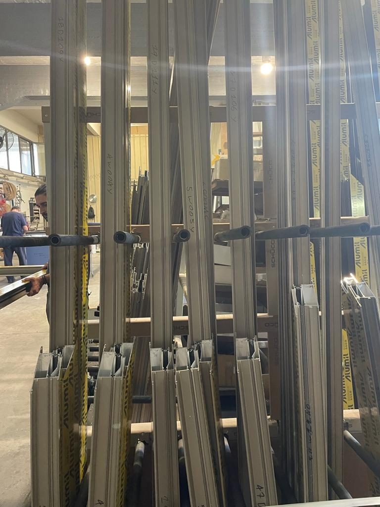 Cut frame members labelled by opening number, racked in the fabrication shop