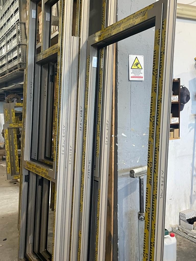 Assembled Alumil door frames in protective tape, tagged with opening numbers
