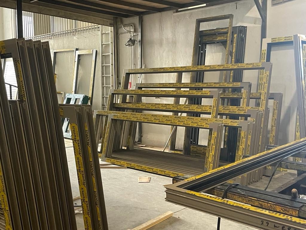 Large assembled Alumil window and door frames lined up in the fabrication hall