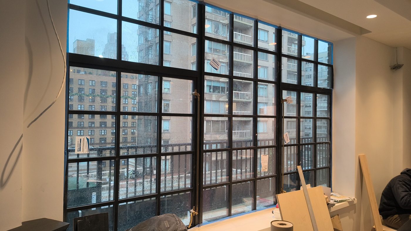 Wall of custom steel windows with continuous divided-lite grid seen from inside the penthouse at 205 East 69th Street