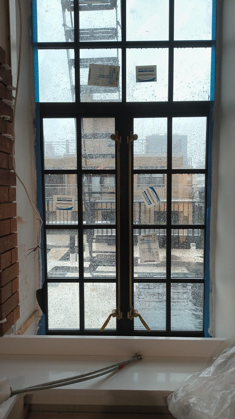 Tall steel French casement with transom and brass cremone bolts inside the penthouse at 205 East 69th Street