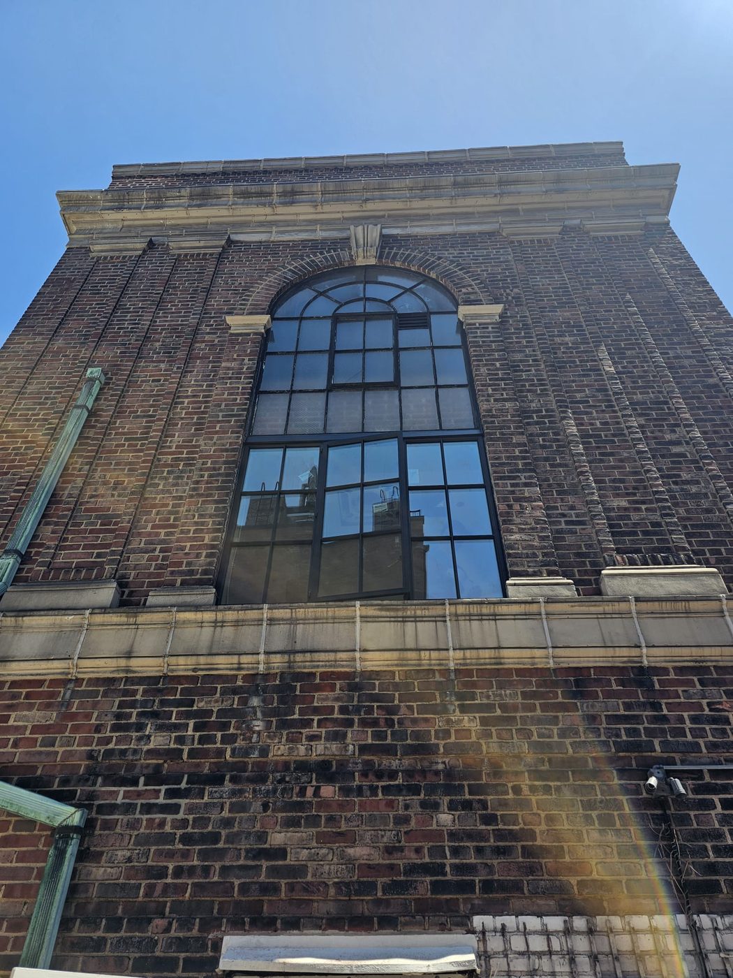 Original 1928 arched steel window with wired glass on the upper facade of 205 East 69th Street, the reference for the new muntin pattern