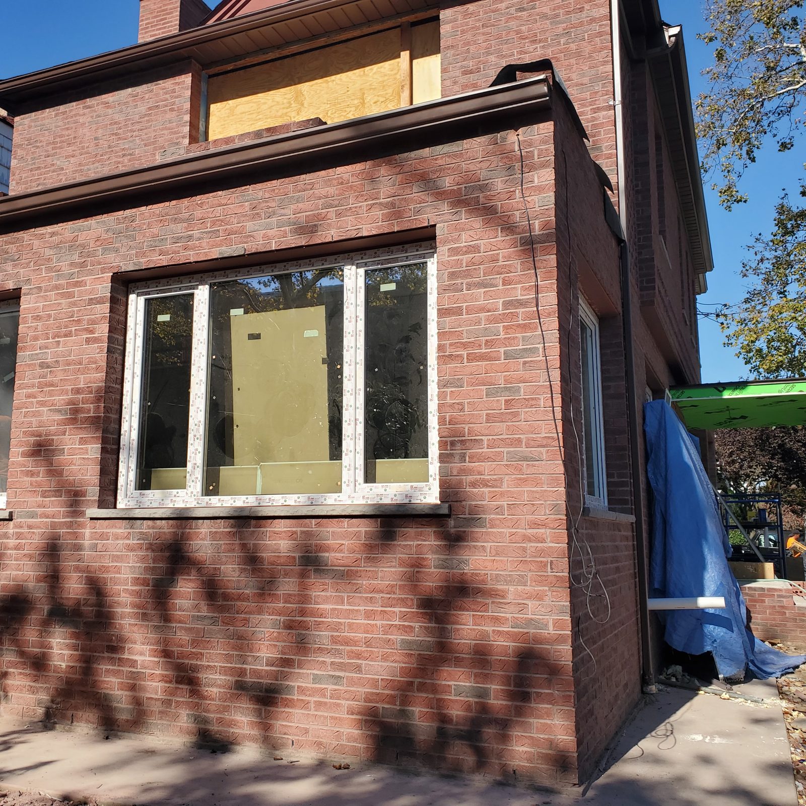 Three-part white uPVC window in the brick front of the house at 24 74th Street, Brooklyn, during renovation