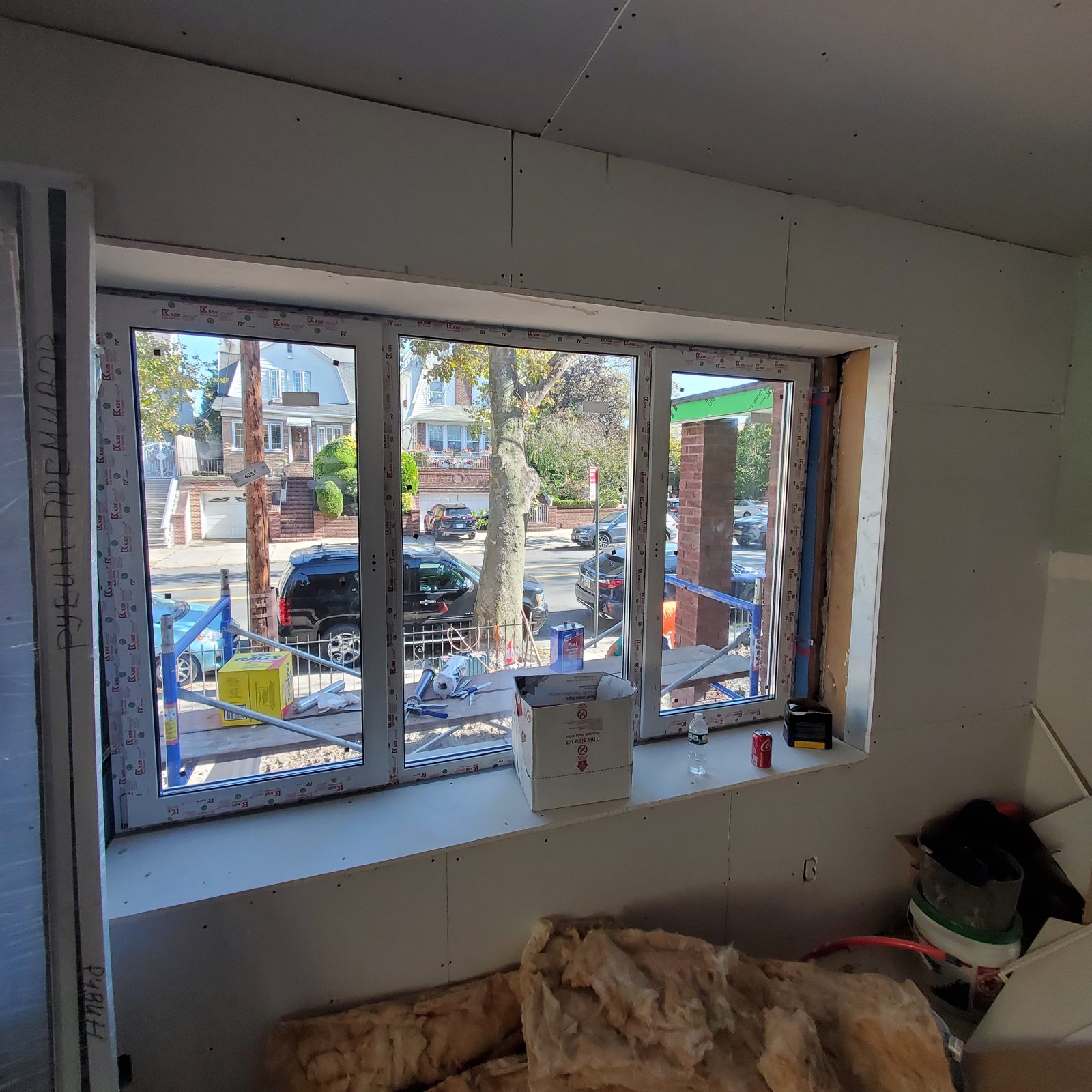 Interior view of the three-part white uPVC window at 24 74th Street, Brooklyn, with drywall going up