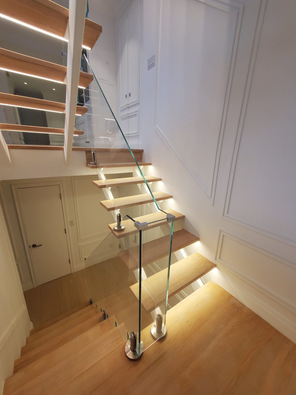 Frameless low-iron glass railing with minimal stainless hardware following an open-riser staircase at 300 East 90th Street, Manhattan