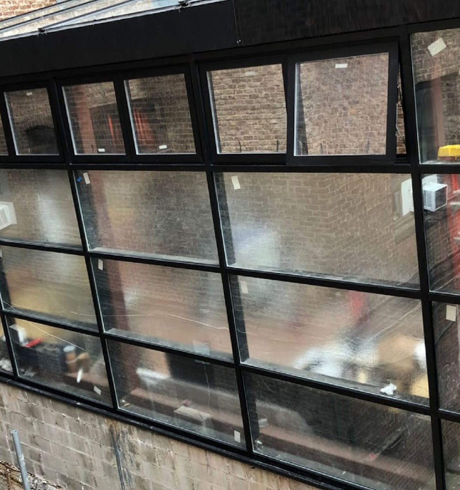 Black aluminum curtain wall of the sunroom at the Civilian Hotel, 305 West 48th Street, Manhattan, with a row of hopper windows along the top