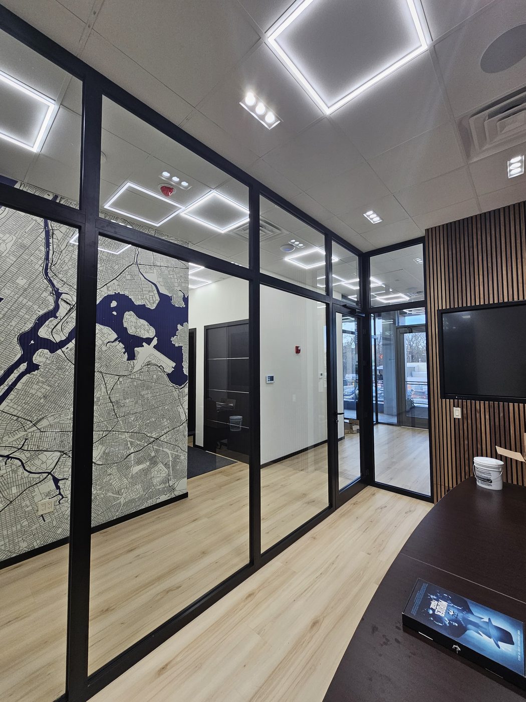 Floor-to-ceiling glass partition with black aluminum frame in front of a map mural at 3121 Ocean Avenue, Sheepshead Bay