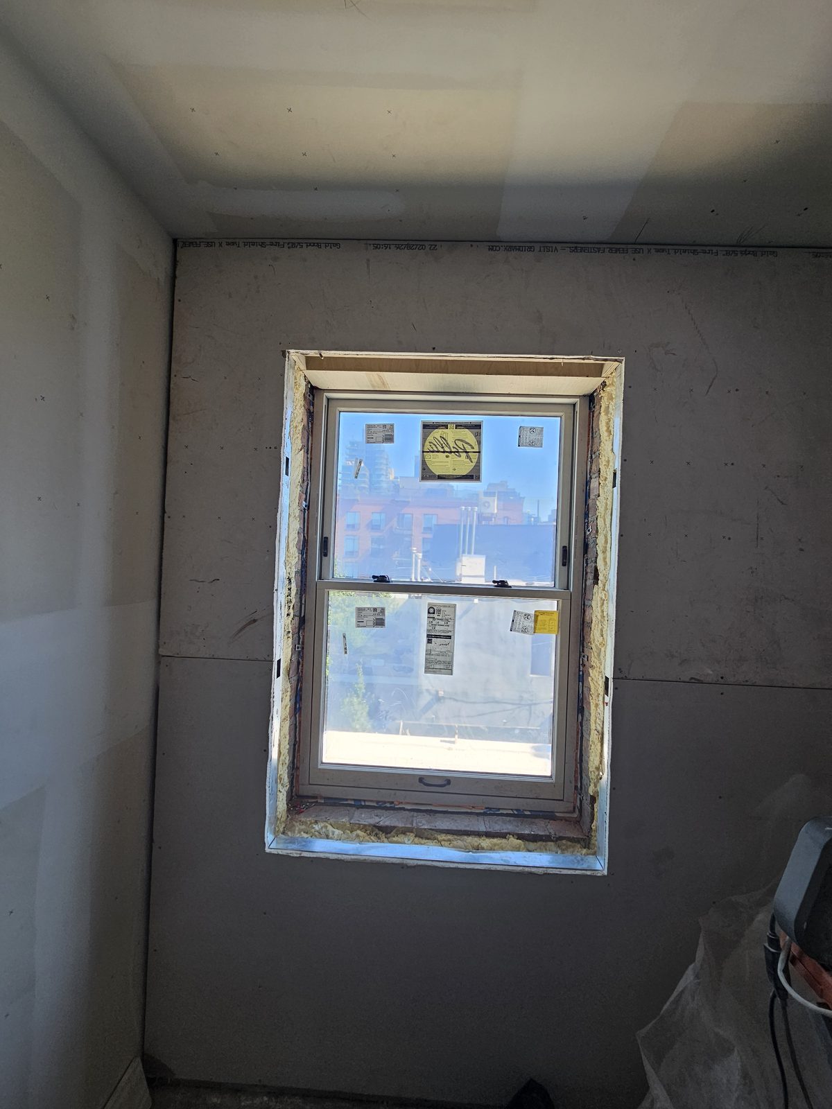 Pella double-hung window seen from inside at 343 Hoyt Street with light interior frame and rooftops beyond