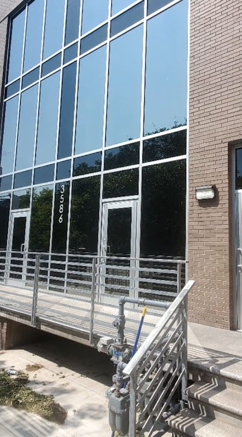 Multi-story aluminum curtain wall with Solarban glass and entrance doors between brick piers at 3586 Nostrand Avenue, Brooklyn