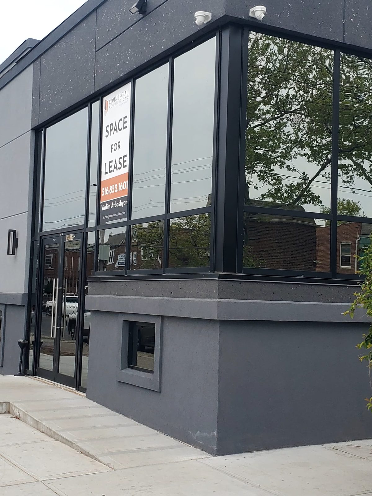 Corner of 3915 Flatlands Avenue with black curtain wall glazing wrapping the corner above the Kawneer entrance doors