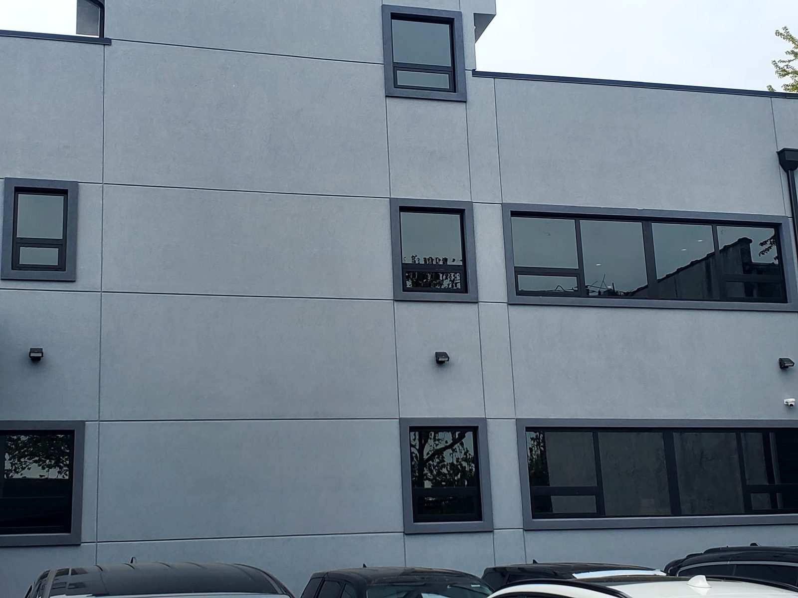 Side elevation of 3915 Flatlands Avenue with Alutech punched windows and ribbon windows in dark frames set in grey stucco