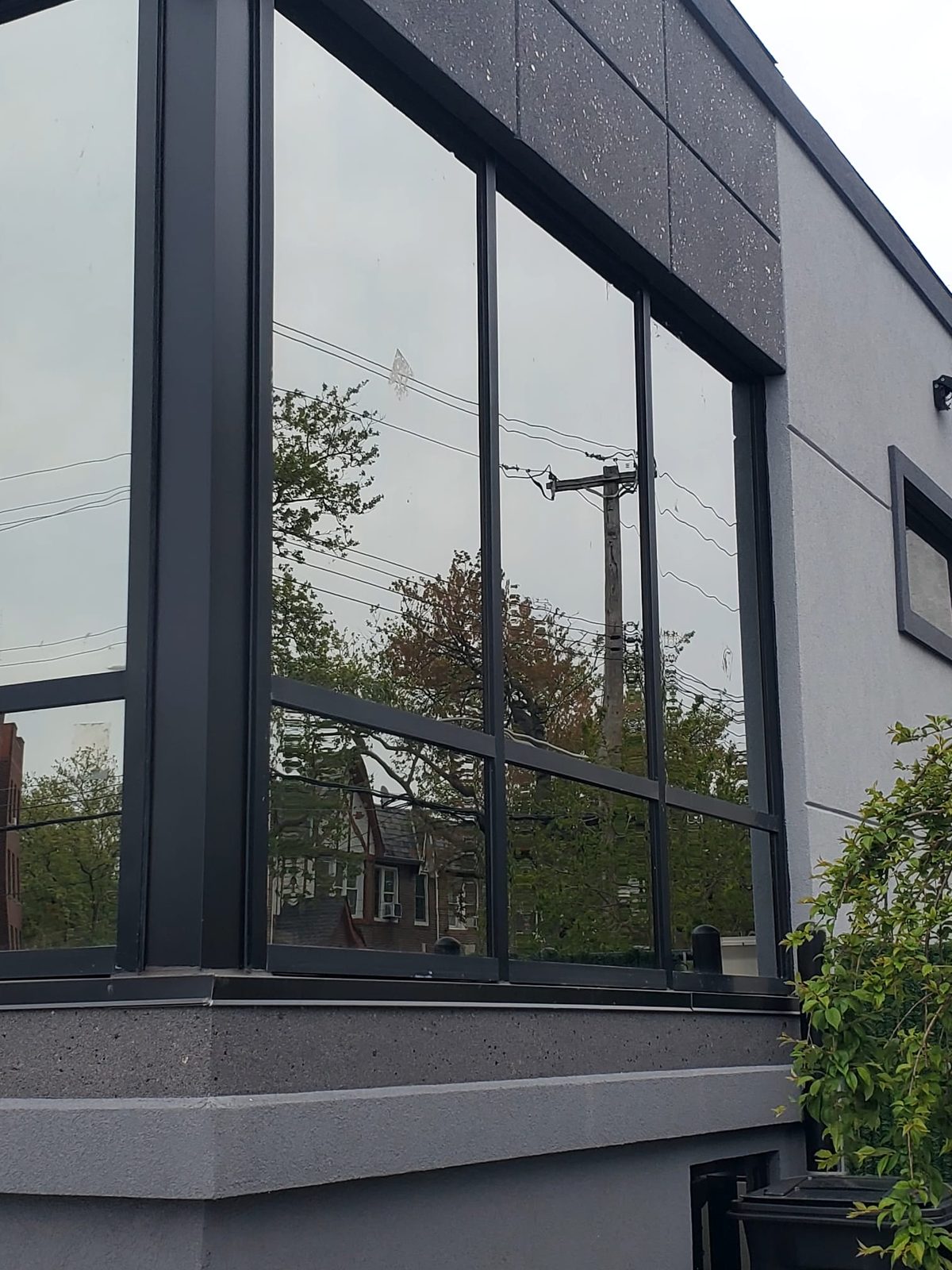 Close view of the curtain wall corner at 3915 Flatlands Avenue showing the reflective Oldcastle glass and black mullions