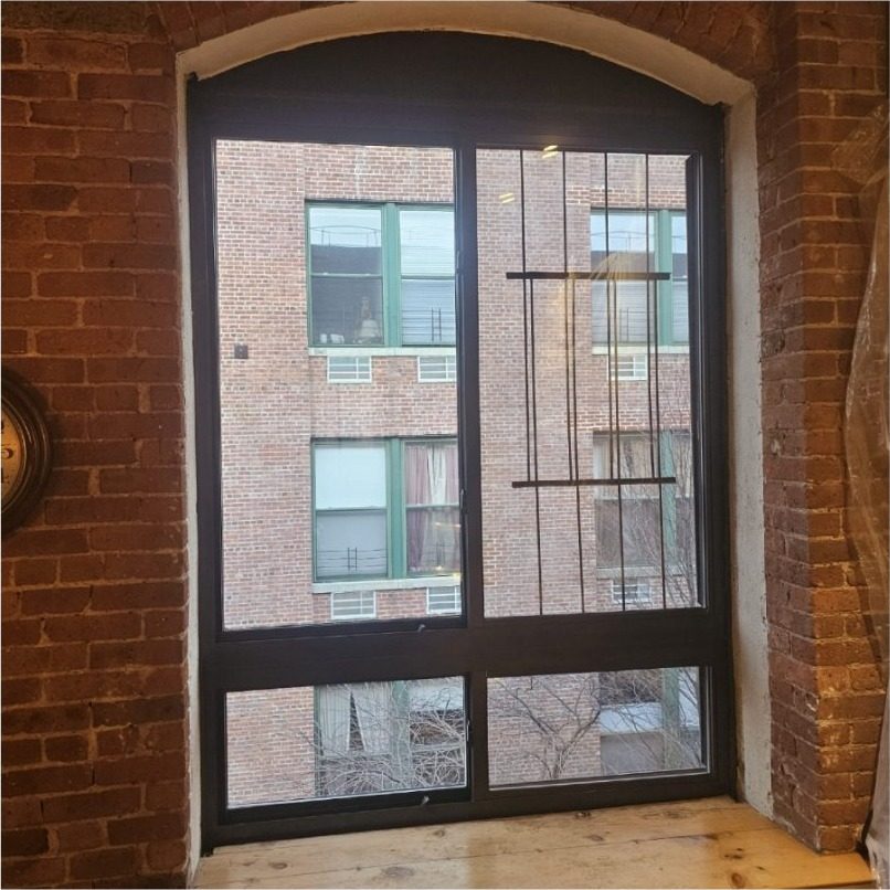 Tall Crystal horizontal sliding aluminium window with fixed lower lites in an arched exposed-brick opening with a timber sill at 420 12th Street, Park Slope, Brooklyn