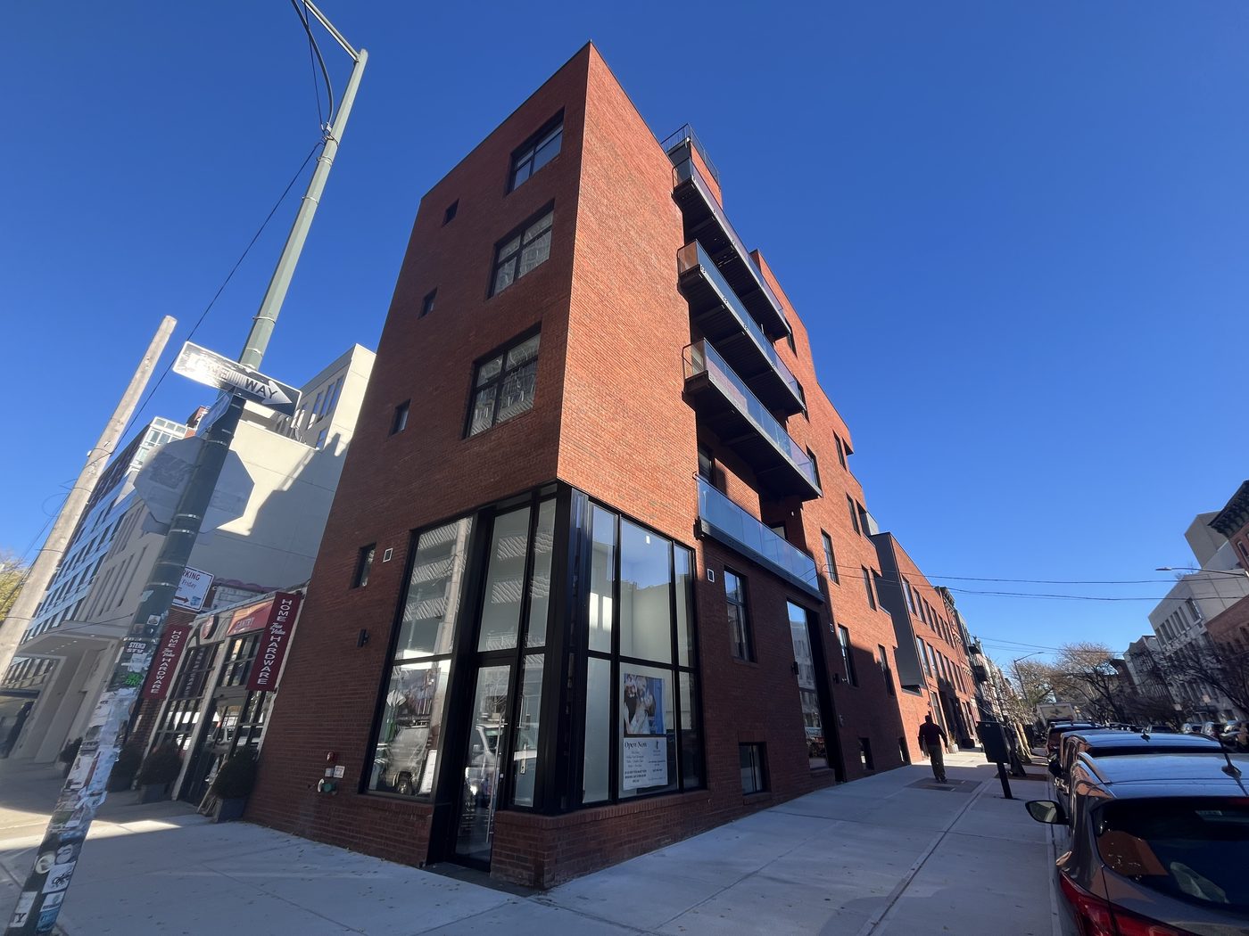 Corner view of 5-13 47th Road, Long Island City, with Cortizo divided-lite aluminum windows, glass balcony railings and full-height glazed corner entrance