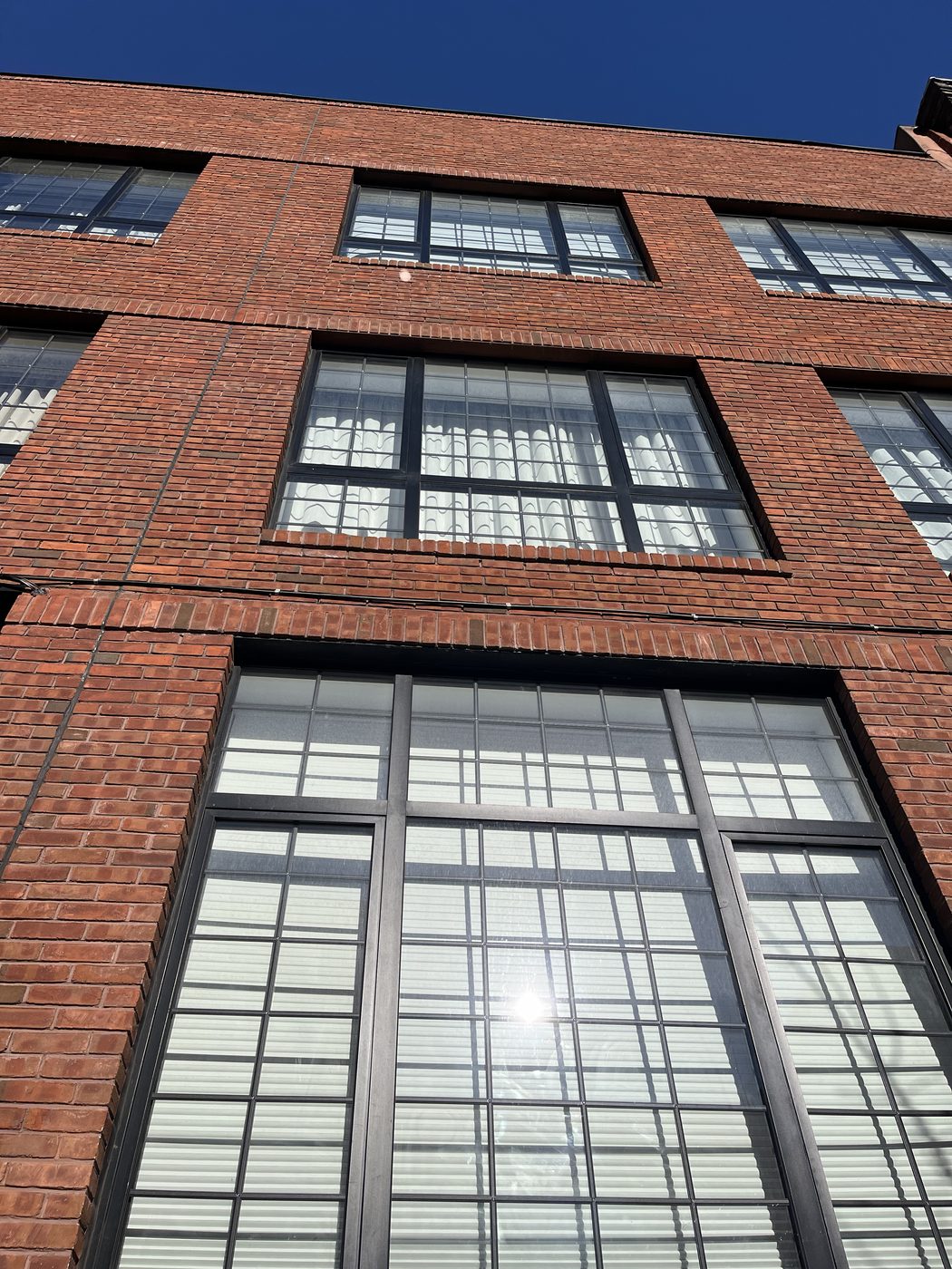 Close view of divided-lite Cortizo aluminum windows in a red brick facade, 5-13 47th Road, Long Island City