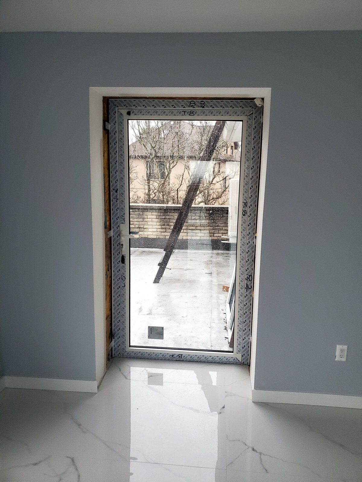 Alutech aluminum glazed door still in its protective wrap after installation at 5101 Beach 51st Street, Sea Gate