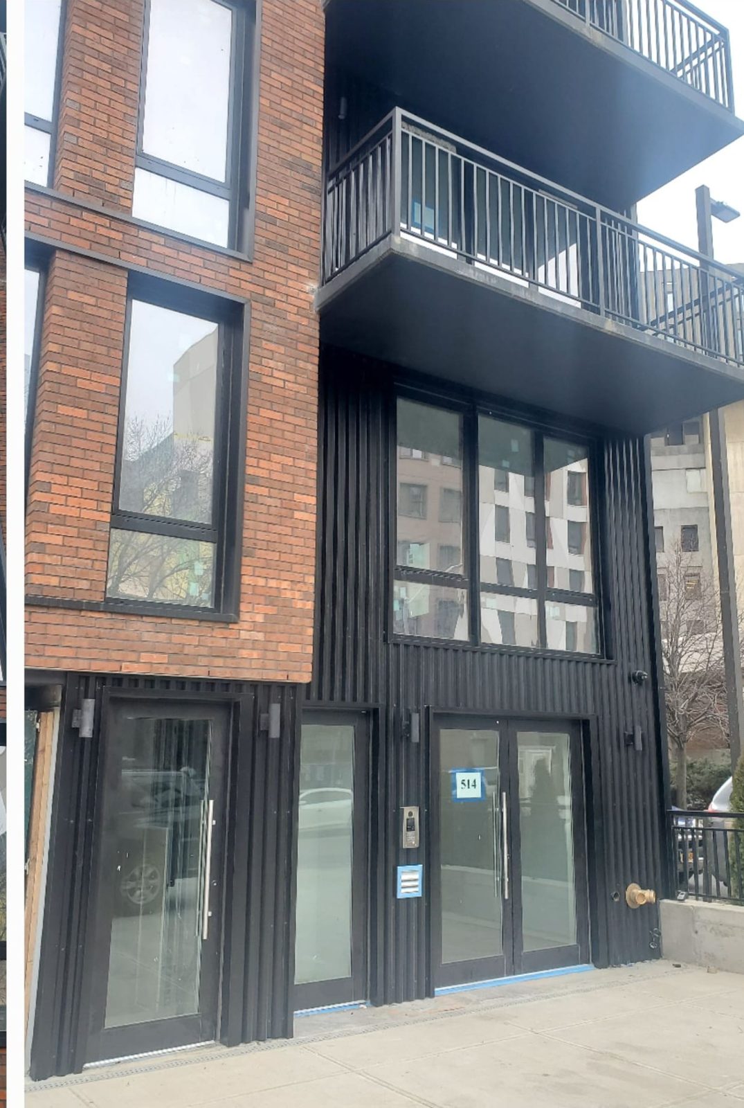 Black ribbed metal panels cladding the entrance bay with commercial storefront doors at 514 Herkimer Street, Brooklyn