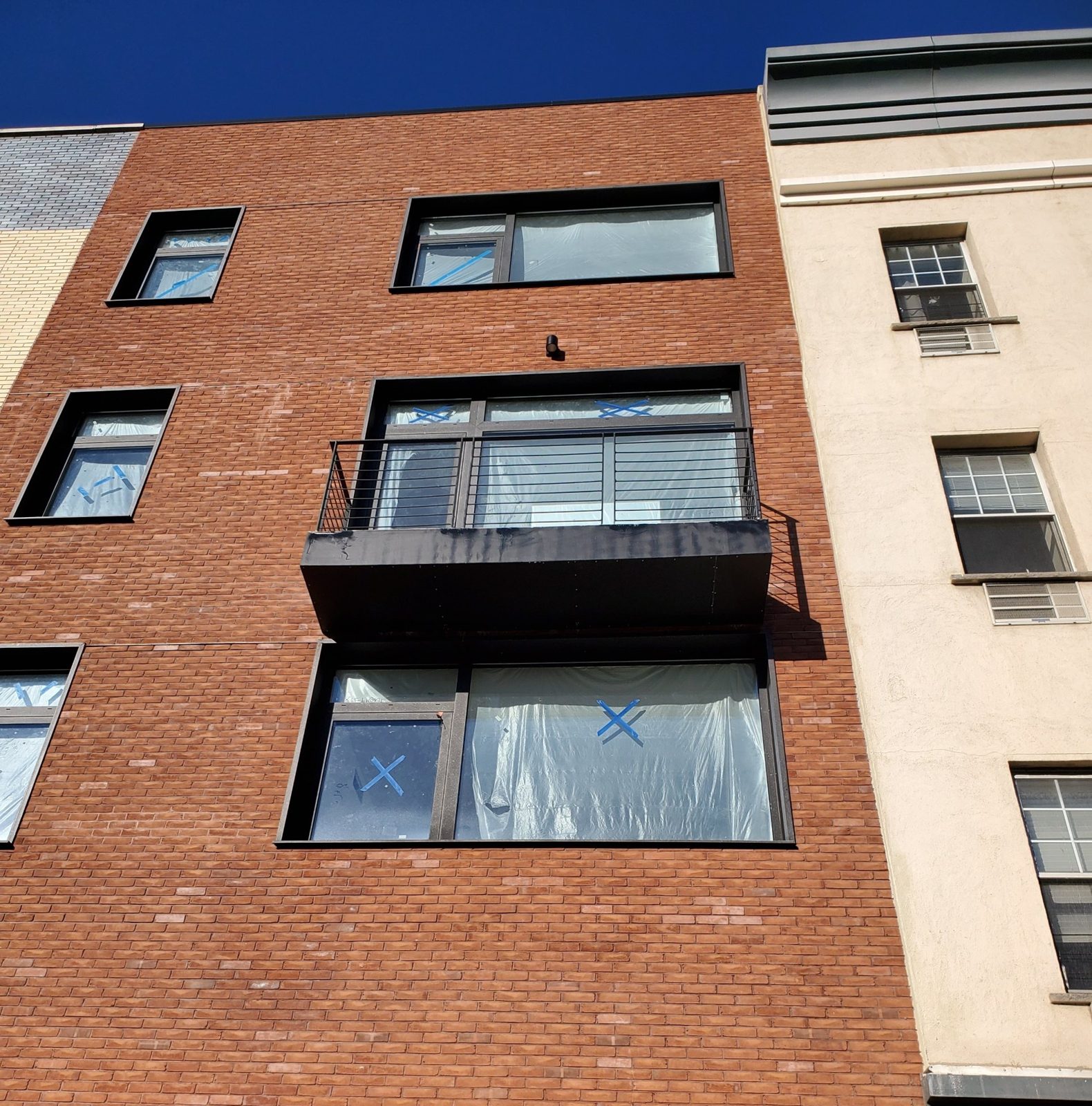 Aluminum windows and balcony door with protective film during construction at 538 5th Avenue, Brooklyn
