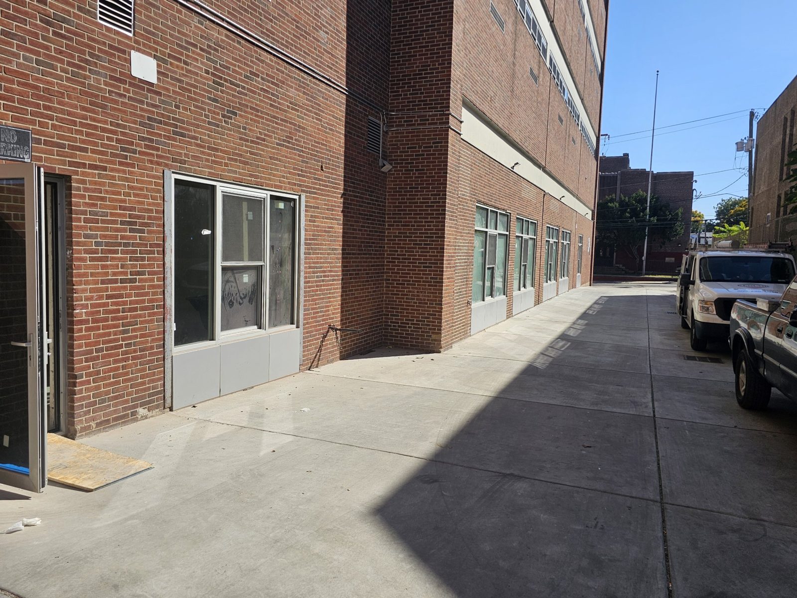 Ground-floor apartment windows at 60 East Haines Street, Germantown, Philadelphia: aluminium double-hung windows between fixed lites with panels below, set in the brick wall of the former school