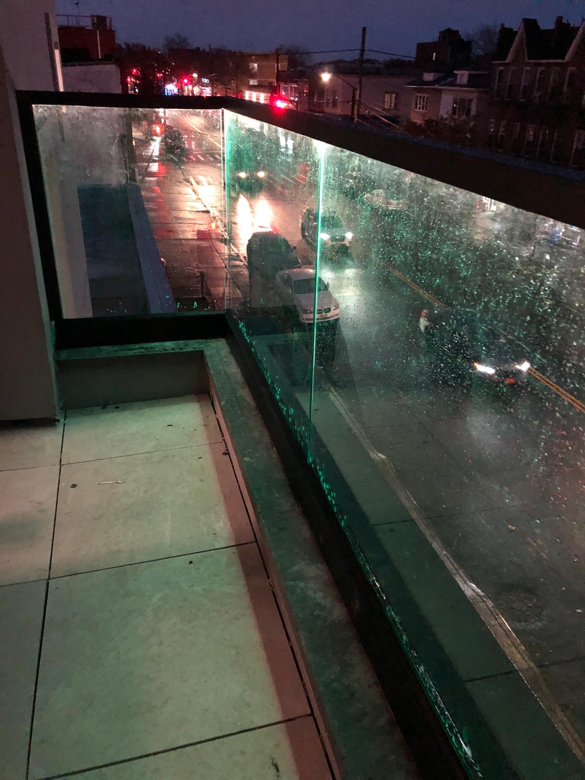 Frameless glass terrace railing with green LED accent lighting at night, 61 Avenue U, Brooklyn