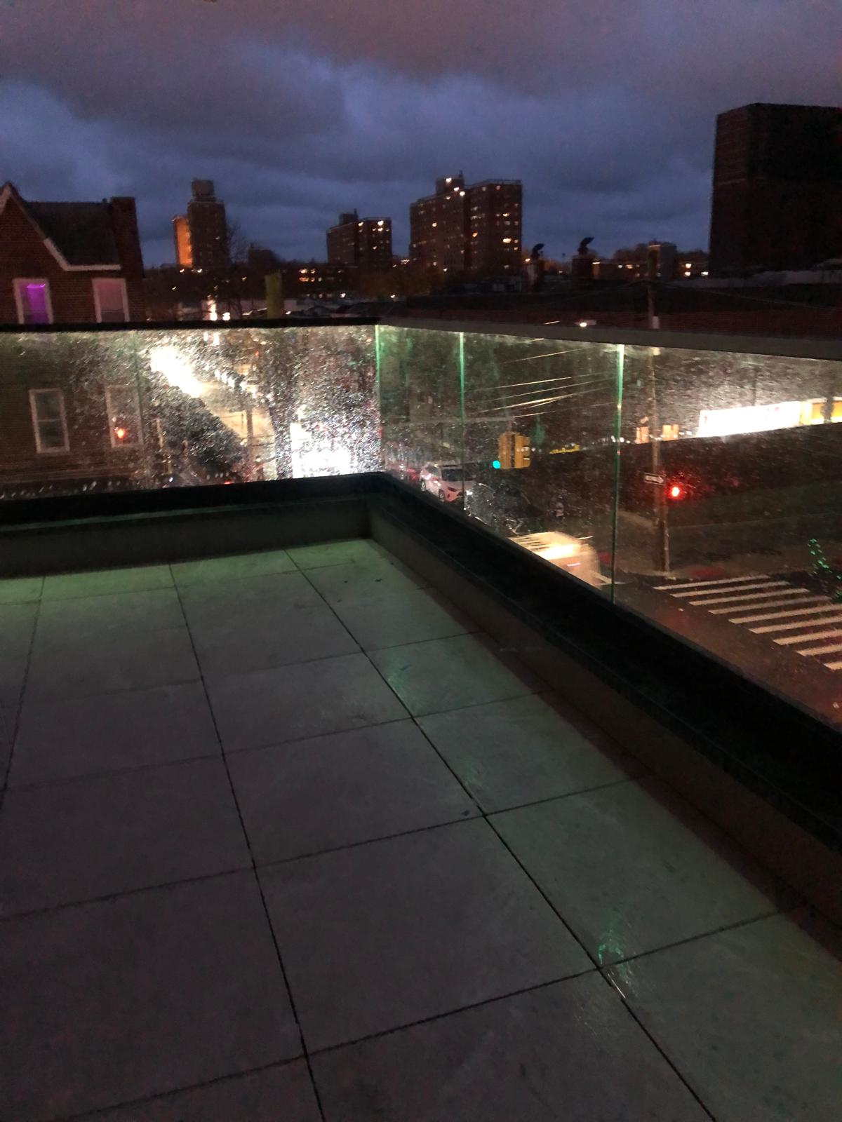 Glass railing with LED lighting and the Brooklyn skyline at night, 61 Avenue U