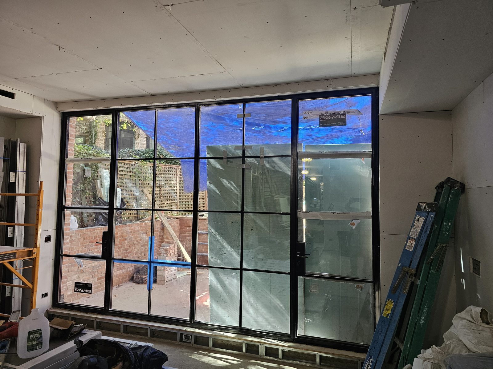 Wide black SIMPAS aluminum sliding door with divided lites opening onto a terrace, seen from inside on East 70th Street