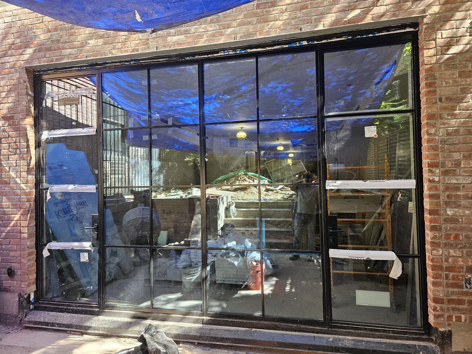 Exterior view from the terrace of a black divided-lite SIMPAS sliding door set in brick on East 70th Street