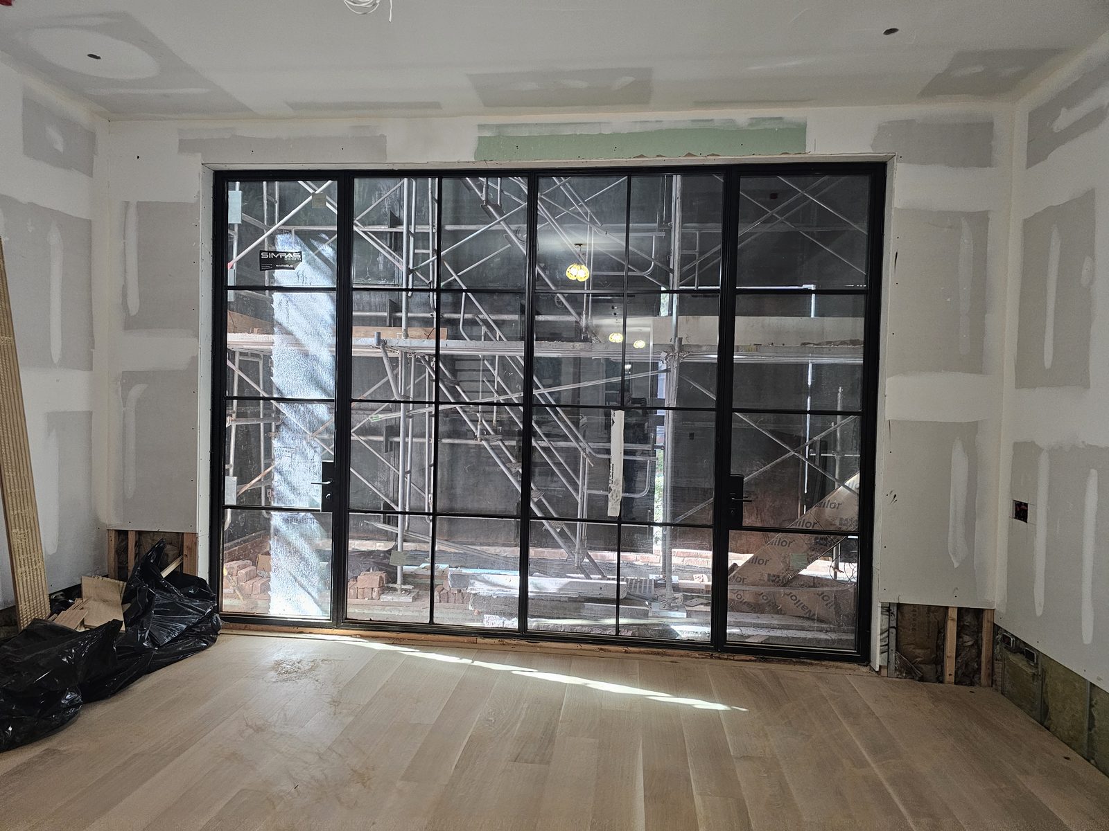 Black SIMPAS divided-lite sliding door in a room with the oak floor laid, East 70th Street Manhattan