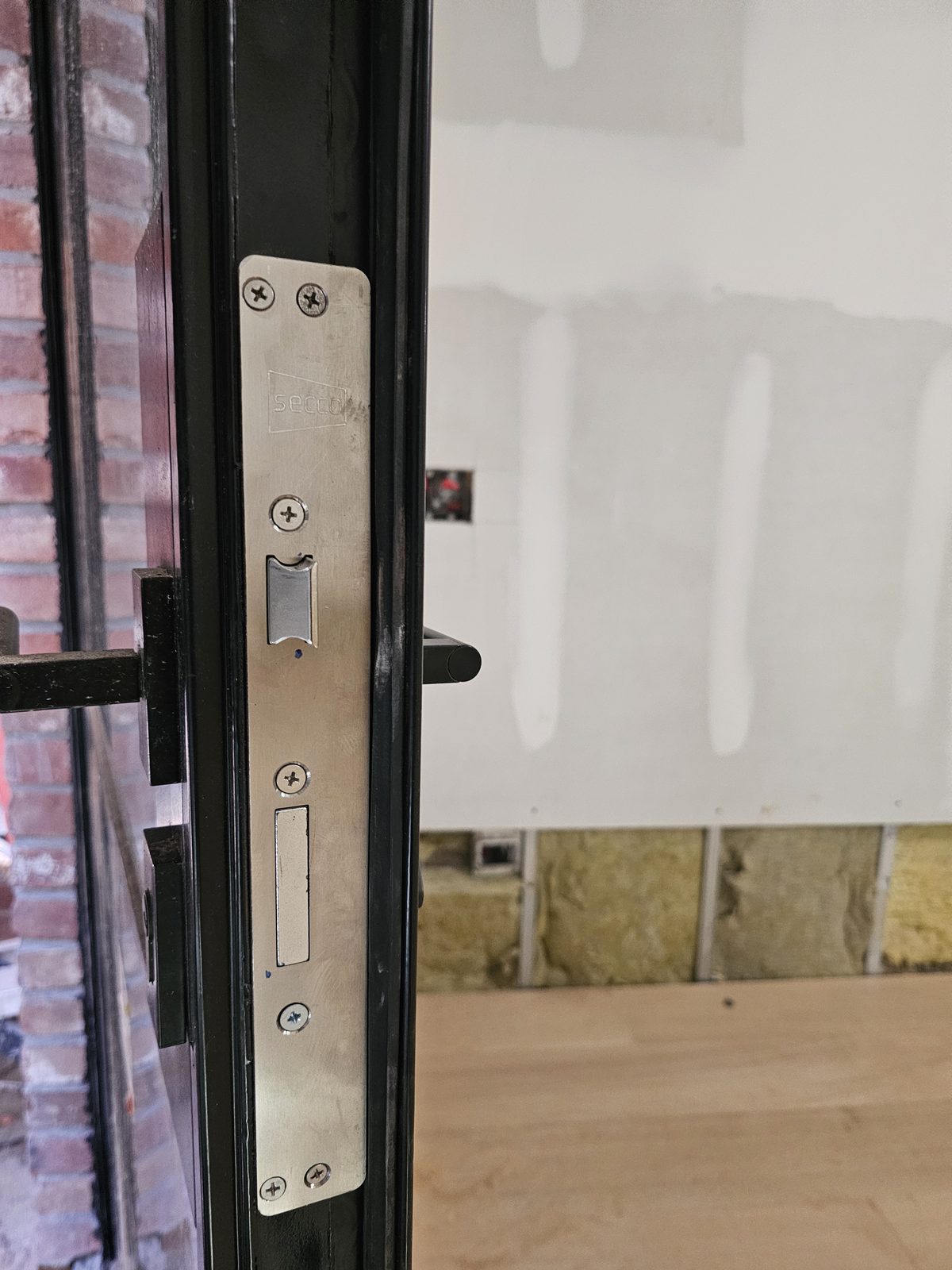 Stainless lock keeper set into the black frame of a SIMPAS sliding door