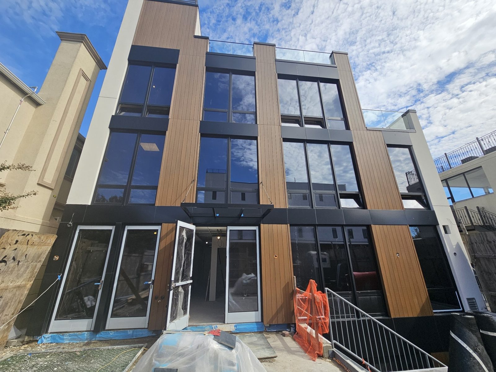 Wide view of the panel facade at 75-65 186th Street, Queens, showing the ground-floor ACM base, window columns and rooftop glass railing