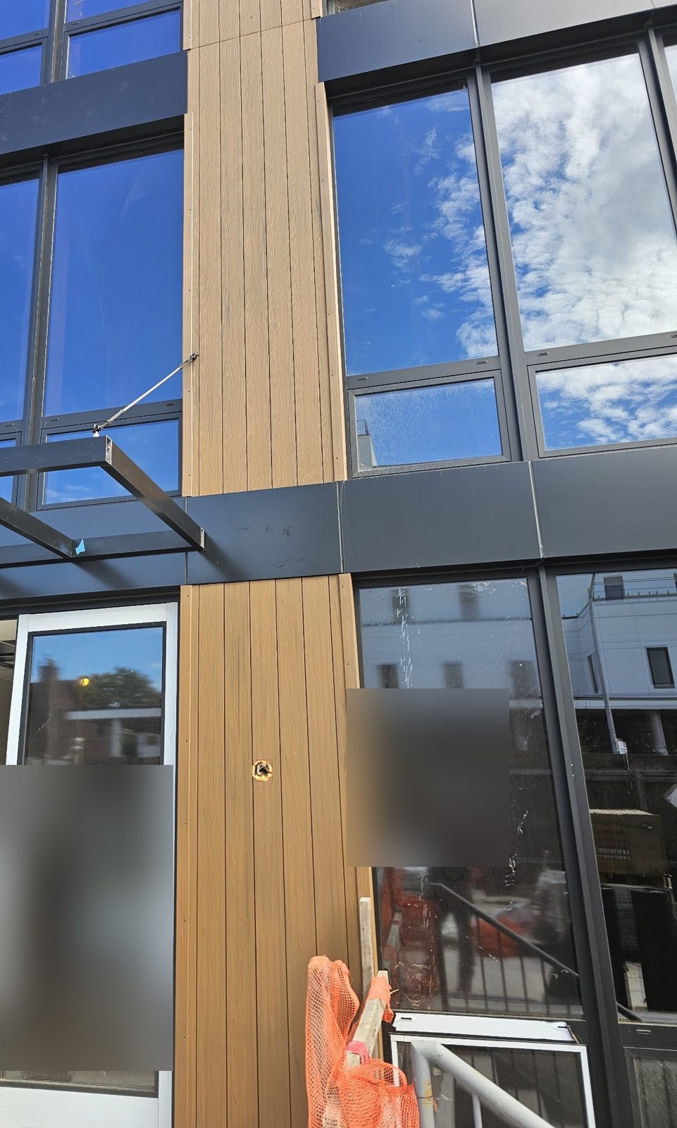Panel joints and canopy cable anchor through the wood-look rigid panels at 75-65 186th Street, Queens