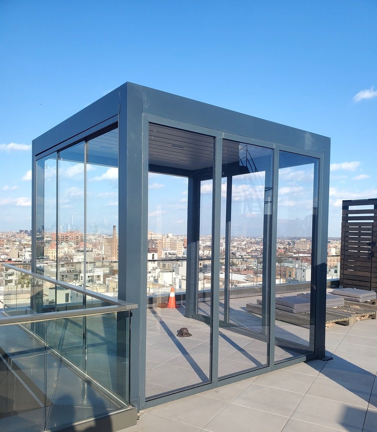Aluminum pergola sunroom with glass walls and a motorized louvered roof on a Brooklyn roof terrace