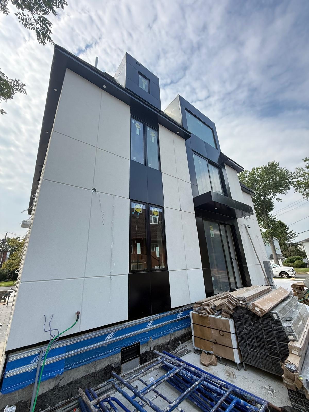 Entrance door open under the canopy, black ACM panel band running behind the canopy frame, Woodmere custom house